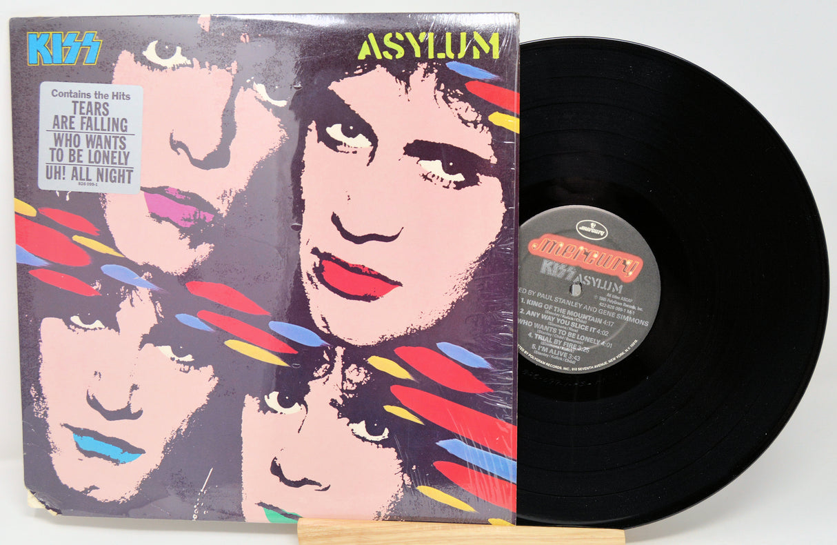 Vinyl record with 'Kiss Asylum' cover showing band members' faces.