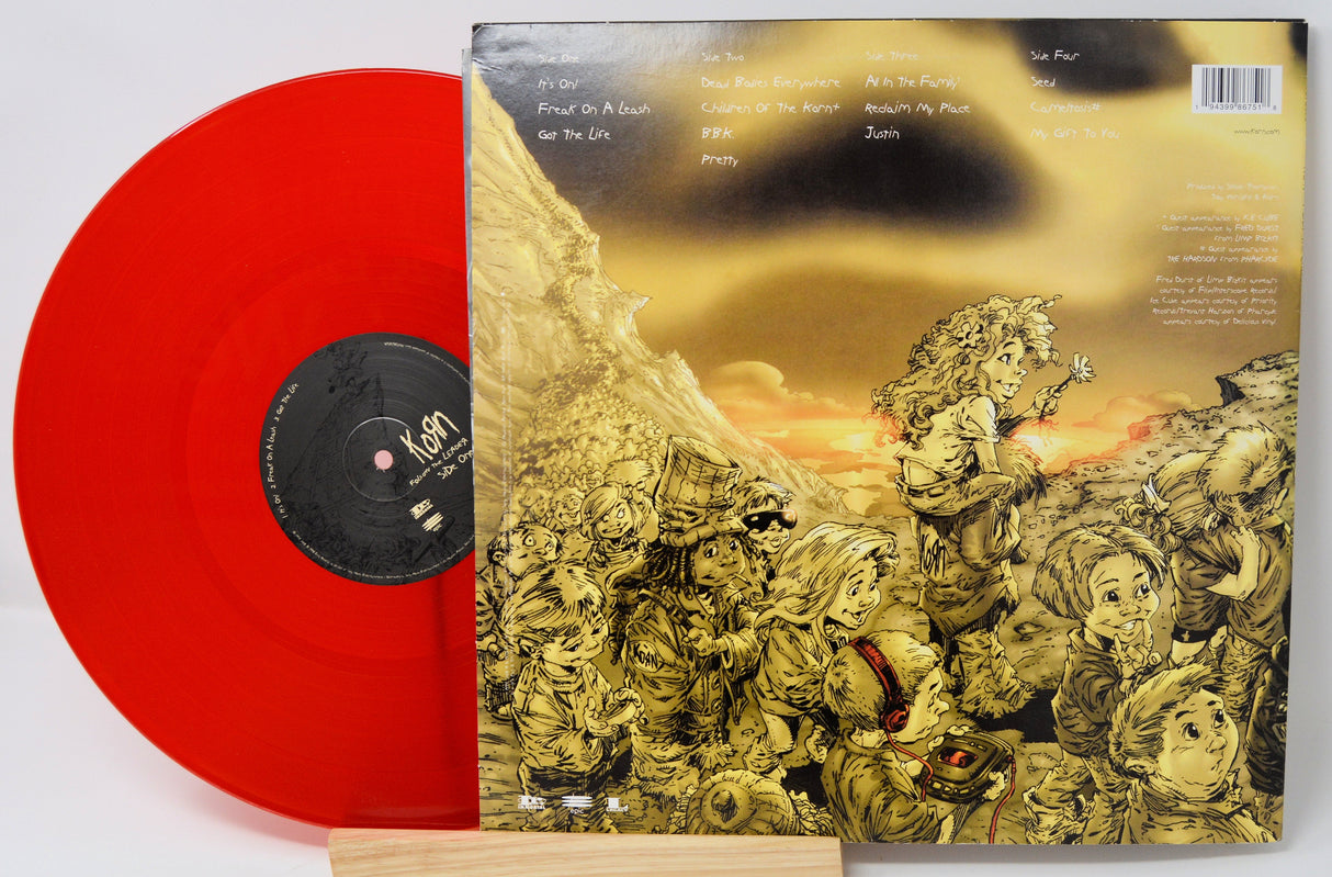 Back cover of Korn's Follow the Leader album next to red vinyl record