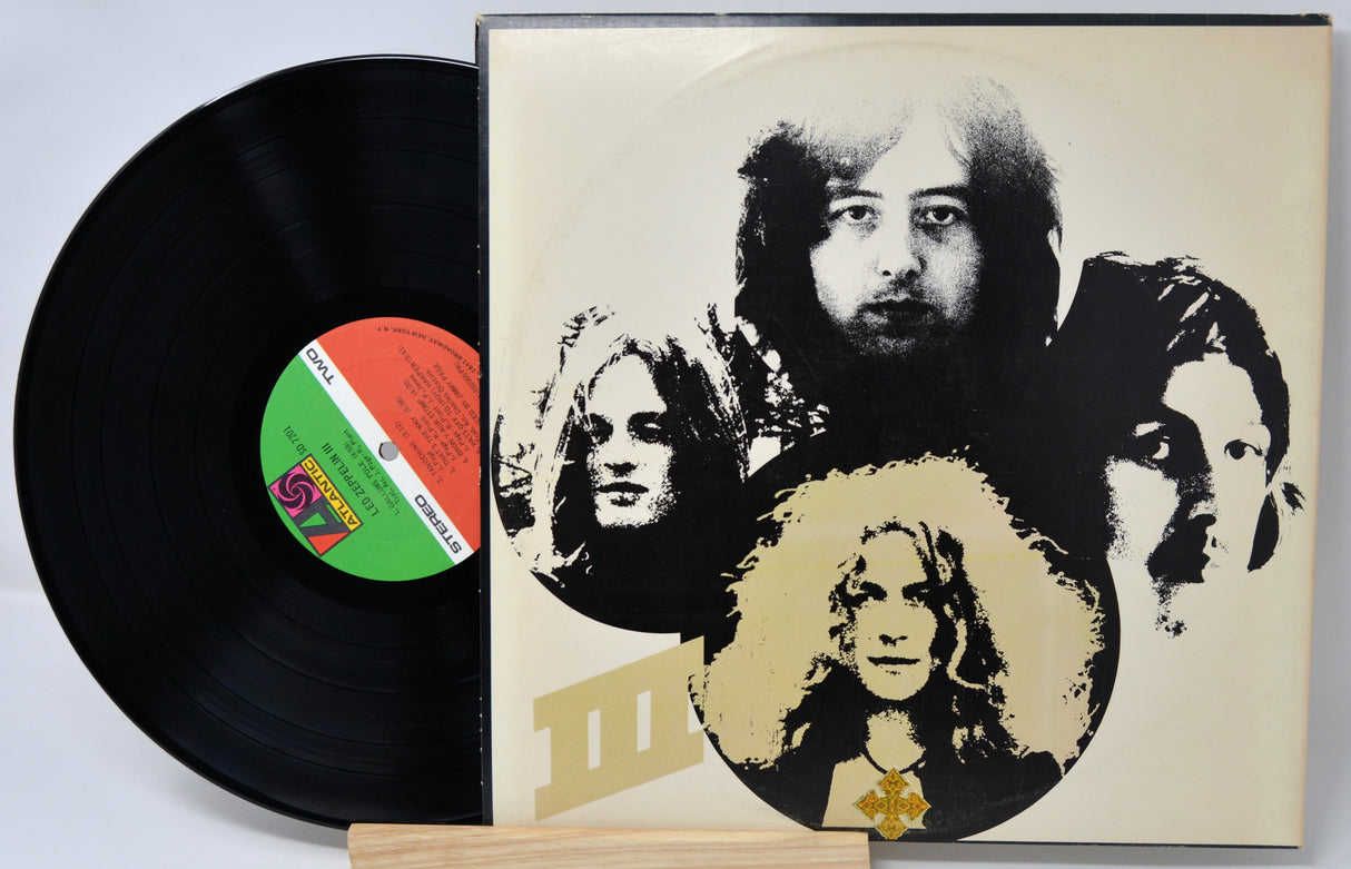 Vinyl record with a cover featuring black and white portraits of four individuals on a beige background.