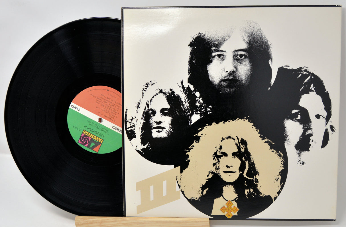 Vinyl record with a cover featuring black and white portraits of band members on a white background.
