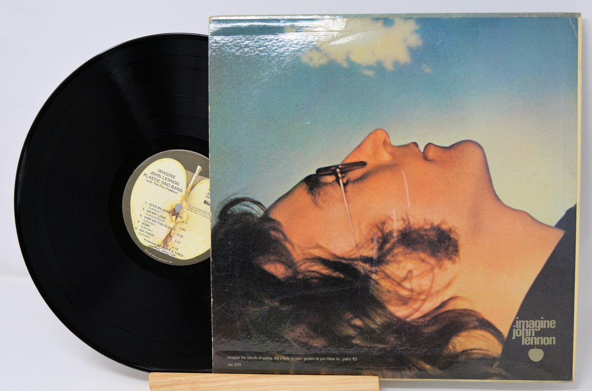 Vinyl record with cover featuring a close-up of a person's face, including sunglasses, on a light gray background.