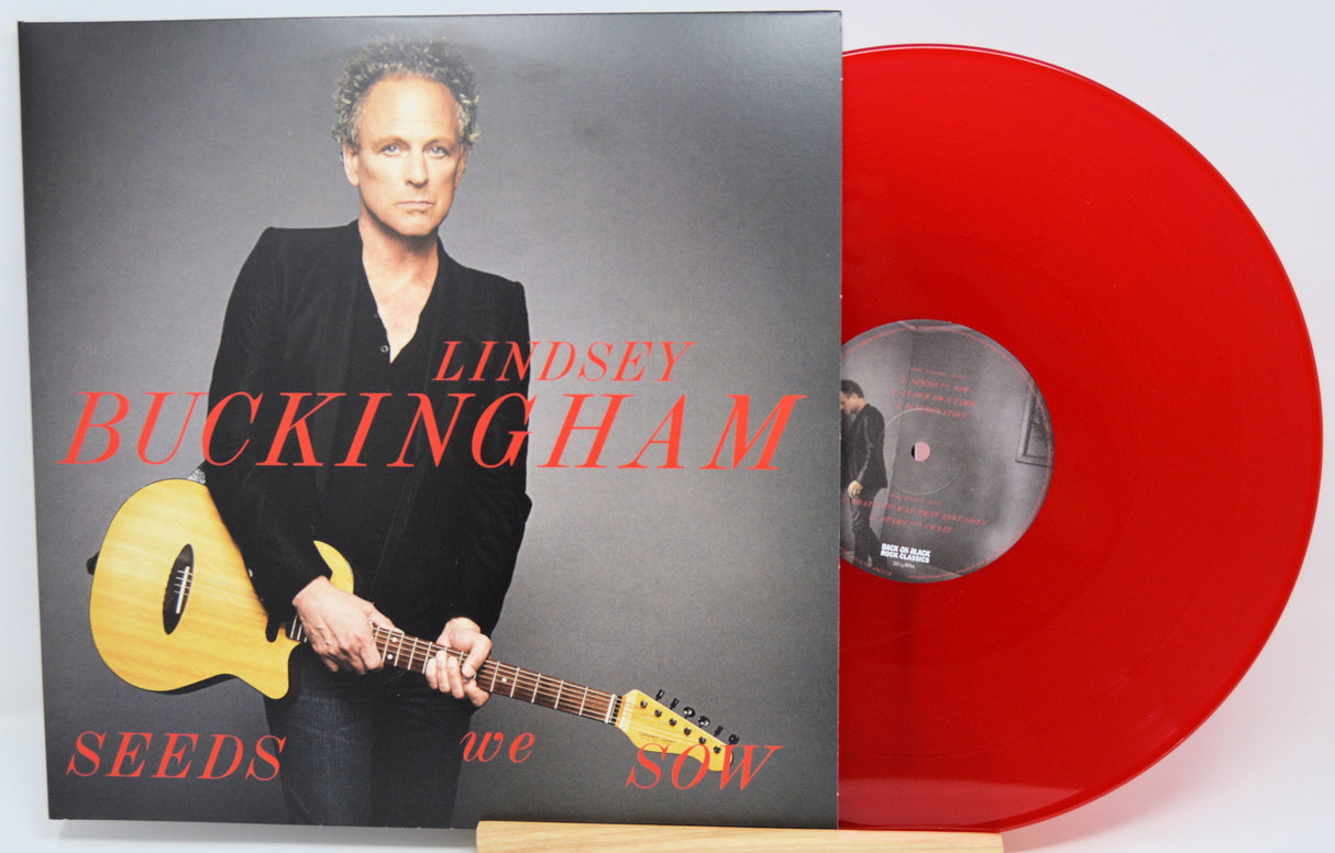 Lindsey Buckingham's 'Seeds We Sow' 12-inch vinyl record shown with its album cover and a translucent red vinyl disc on a white background.