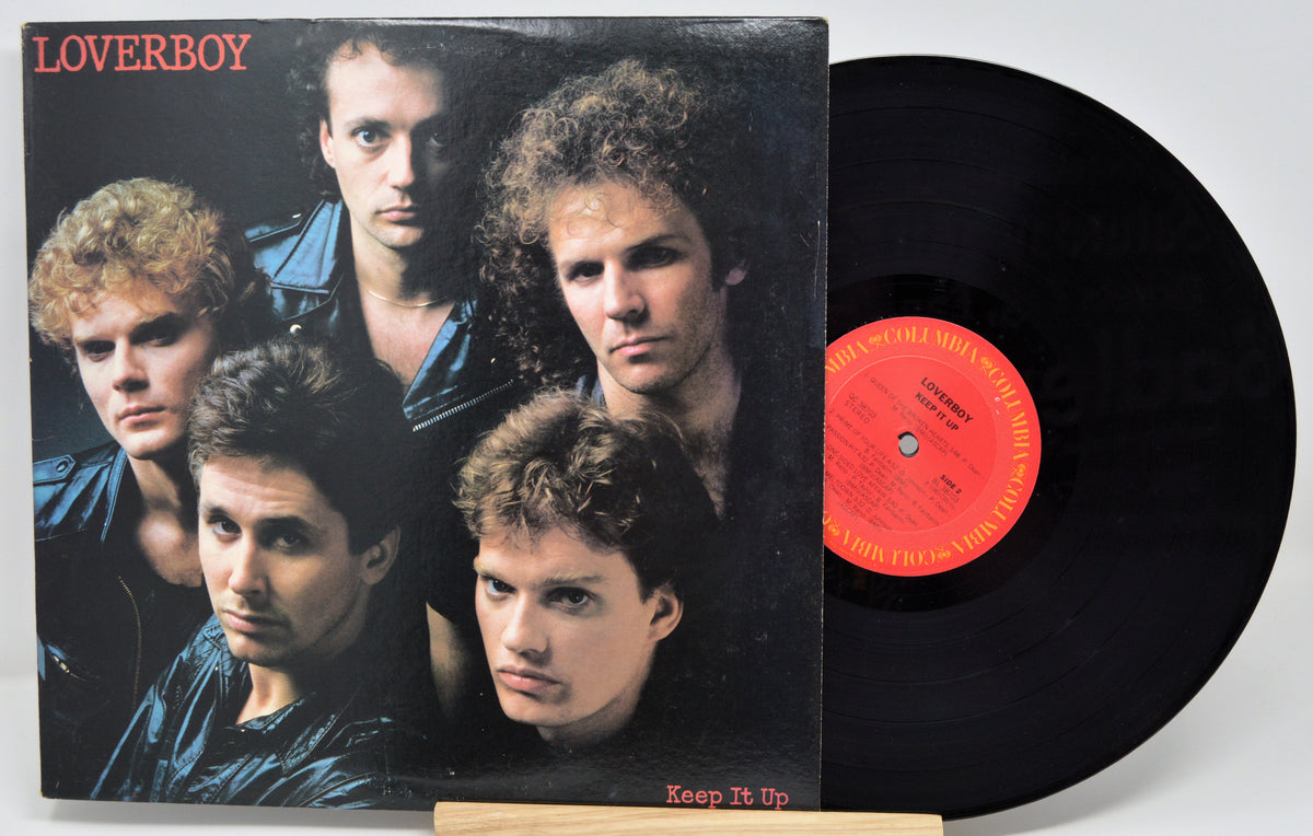 A vinyl record and its cover featuring members of the band Loverboy with the album title 'Keep It Up' displayed.