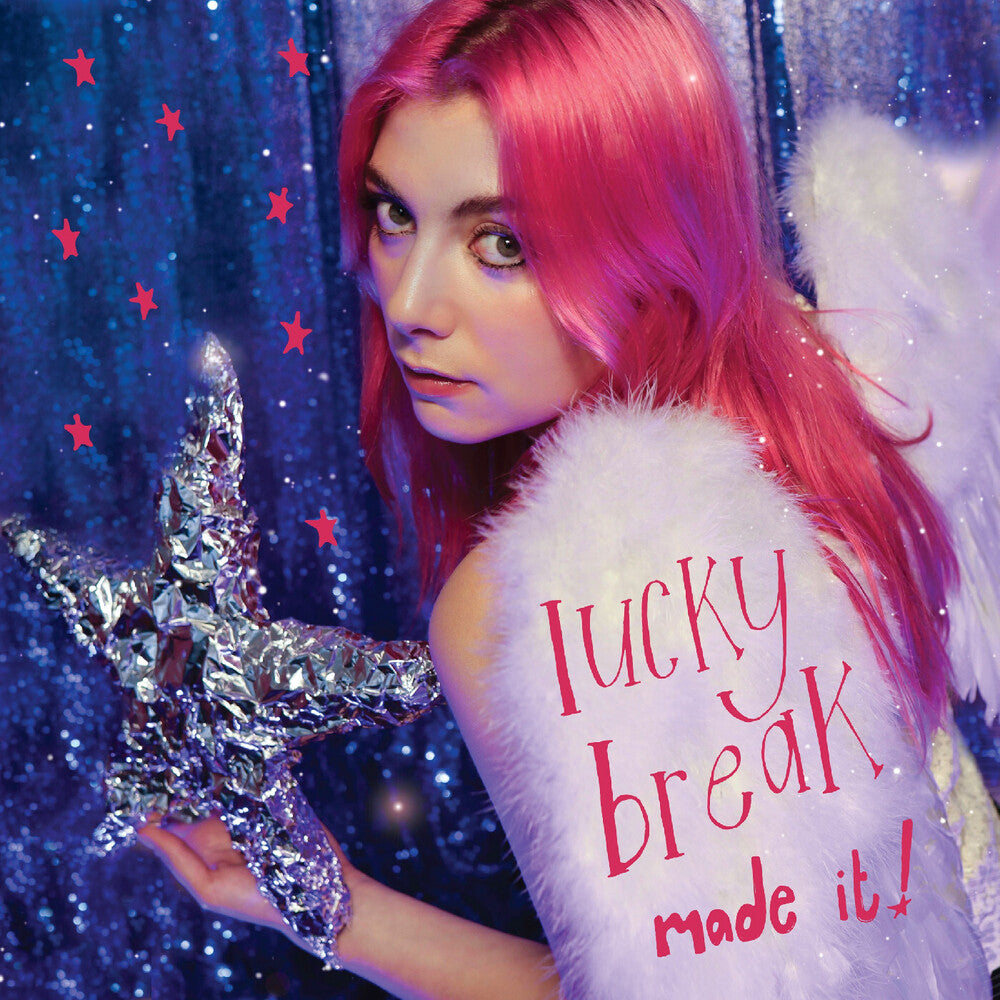 Person with pink hair holding a silver star-shaped object against a blue glittery background with stars.