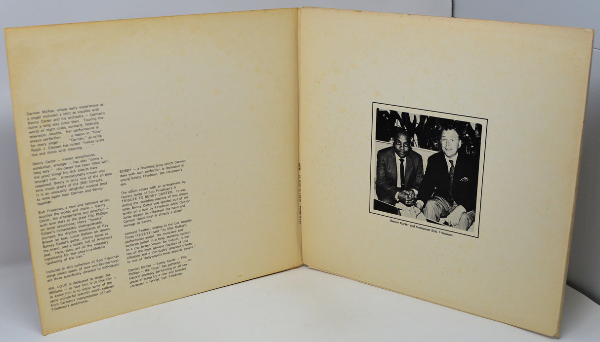 Open book with text on one page and a black and white photo of two men on the other, against a gray background.