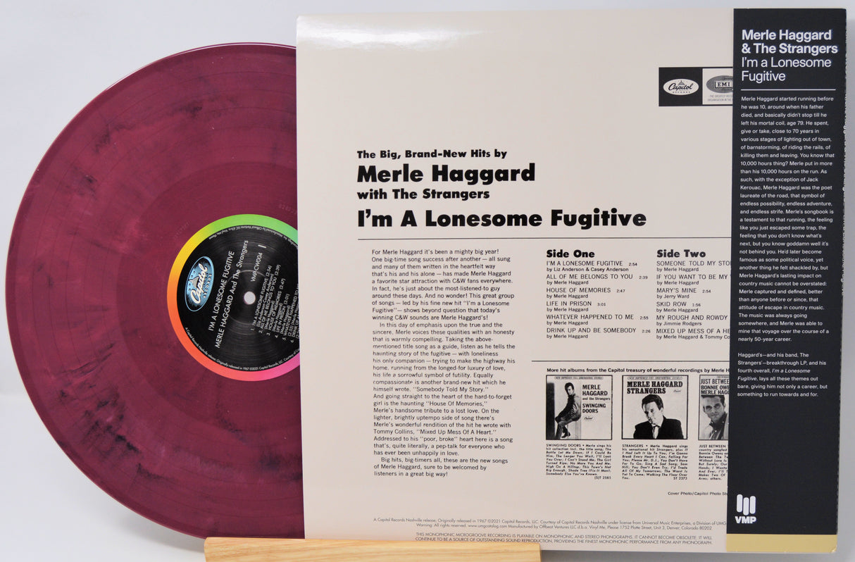 Merle Haggard & The Strangers 'I'm A Lonesome Fugitive' vinyl record LP shown with the printed album cover insert. The record is a maroon/burgundy color with a black center label featuring a rainbow gradient ring.