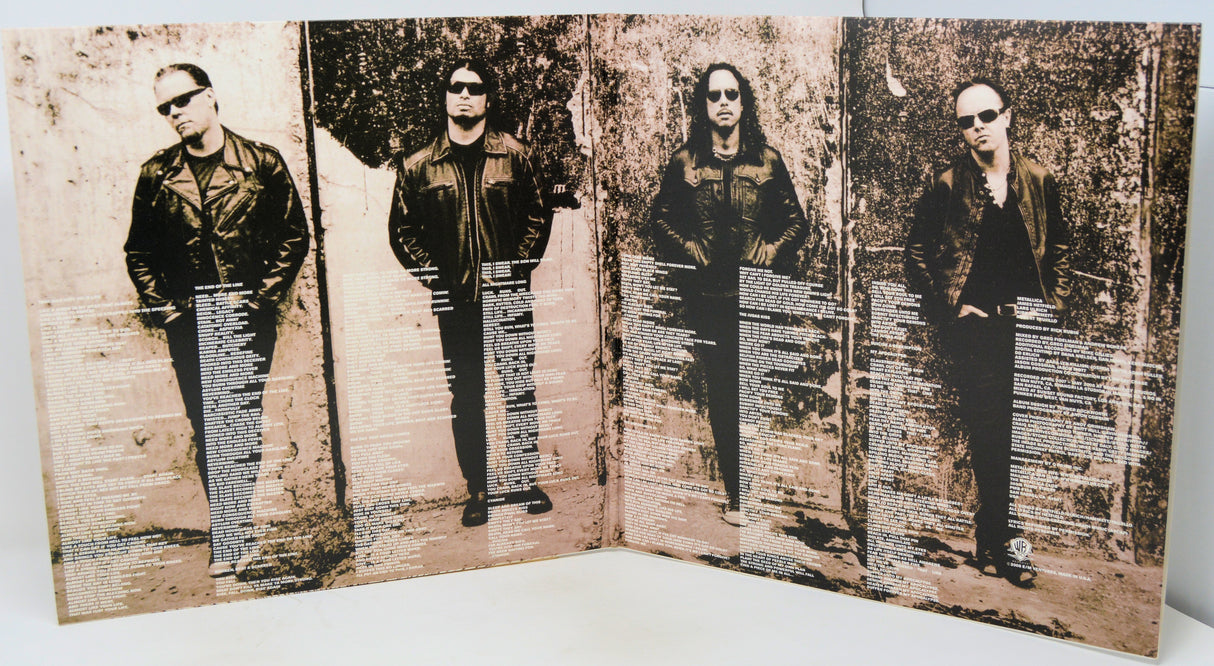 A square printed art piece or poster showing four vertically aligned black-and-white portraits of a band member, overlaid with horizontal columns of small text, photographed against a plain light background.