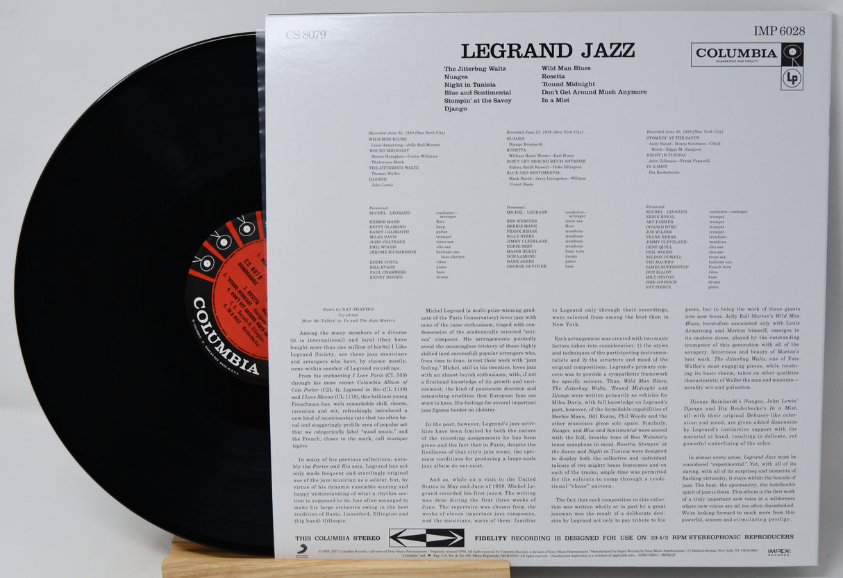 A vinyl record partially pulled from its printed back cover, showing the black record with a red-and-black Columbia label and the white insert printed with track listings and text. The title 'LEGRAND JAZZ' and 'COLUMBIA' are visible.