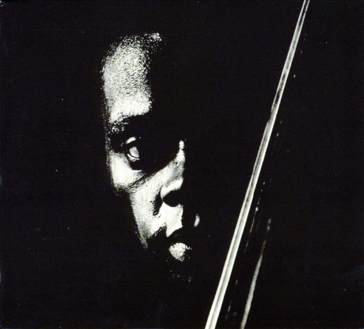 Dramatic black and white close-up portrait of a musician with intense shadows and a vertical line.