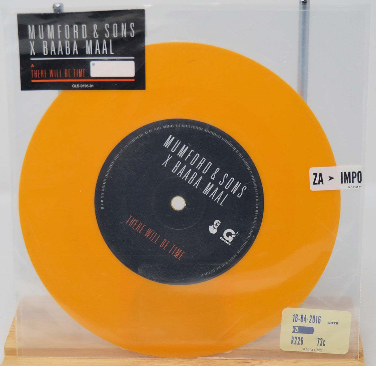 Orange vinyl record with black label featuring 'Mumford & Sons x Baaba Maal' on a clear background.