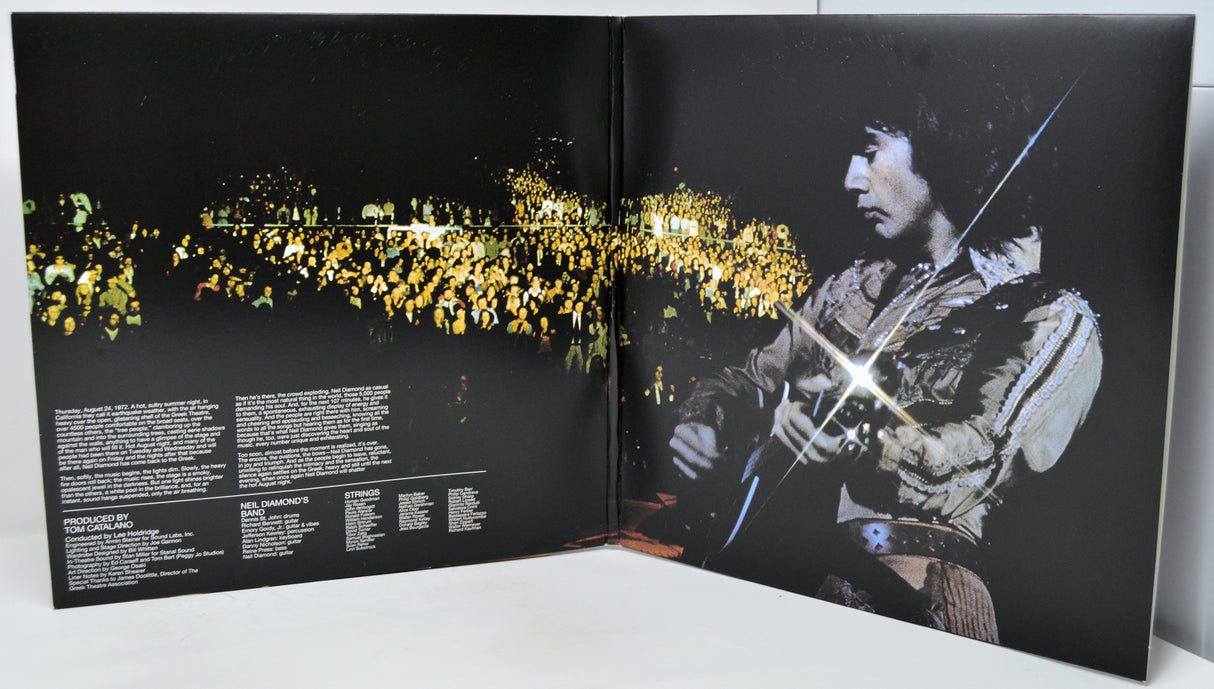 Open book or album with a black and white image of a person playing guitar on one page and a scenic view on the other.