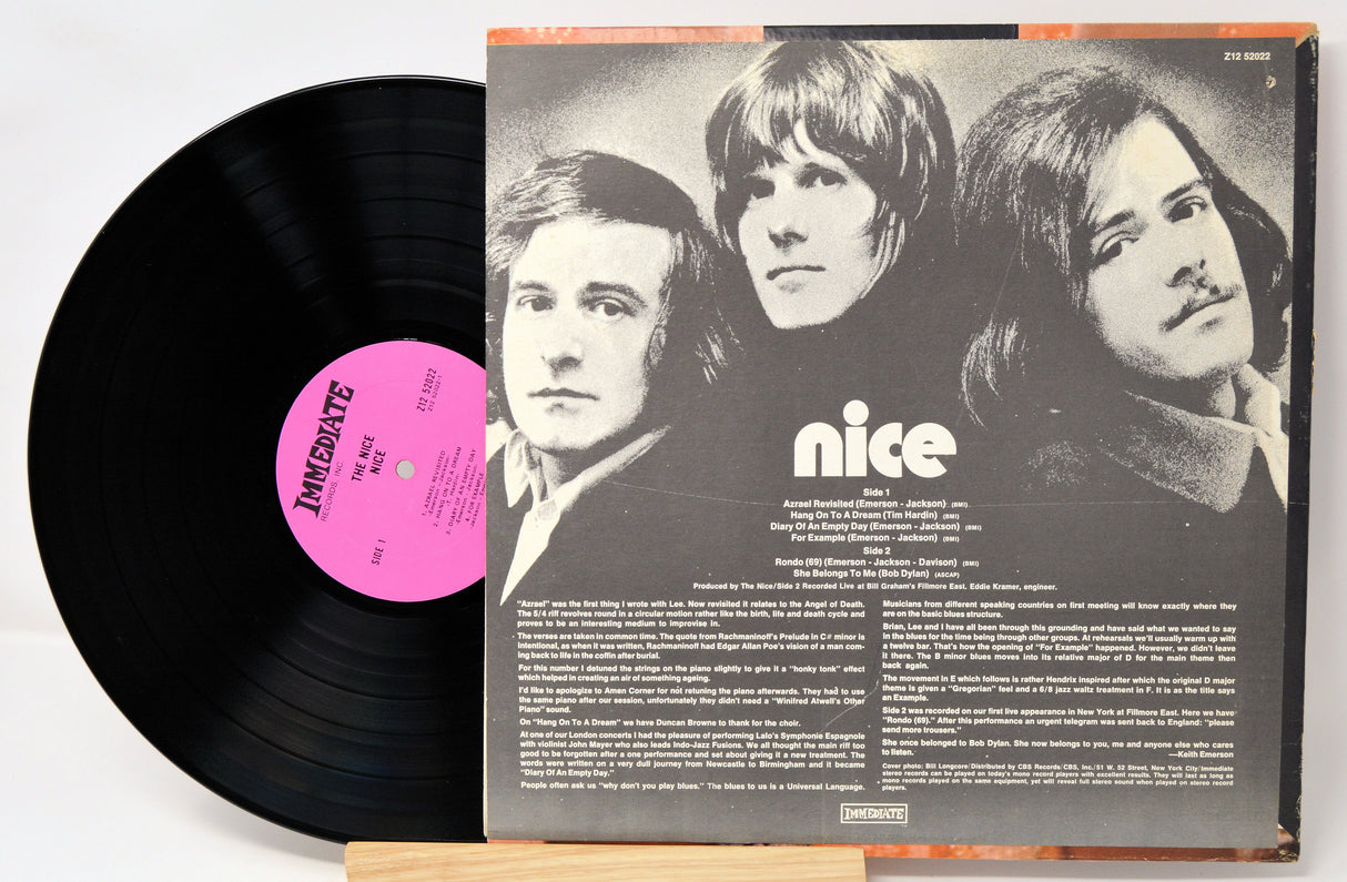 Vinyl record with a black cover featuring three band members and a pink label.
