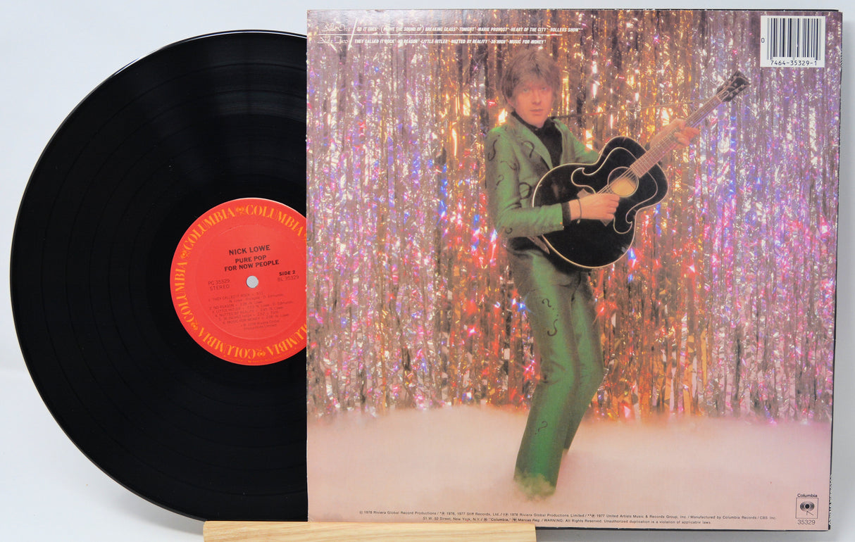 Vinyl record with a colorful album cover featuring a person playing guitar against a glittery curtain.