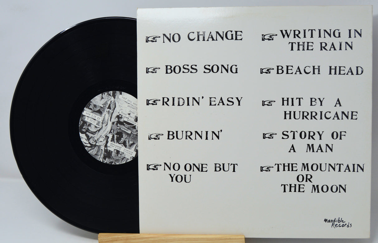 Vinyl record with white label displaying tracklist on a light gray background