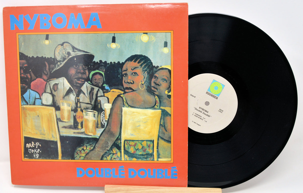 Vinyl record with cover featuring people at a bar, labeled 'NYBOMA Doublé Doublé'.