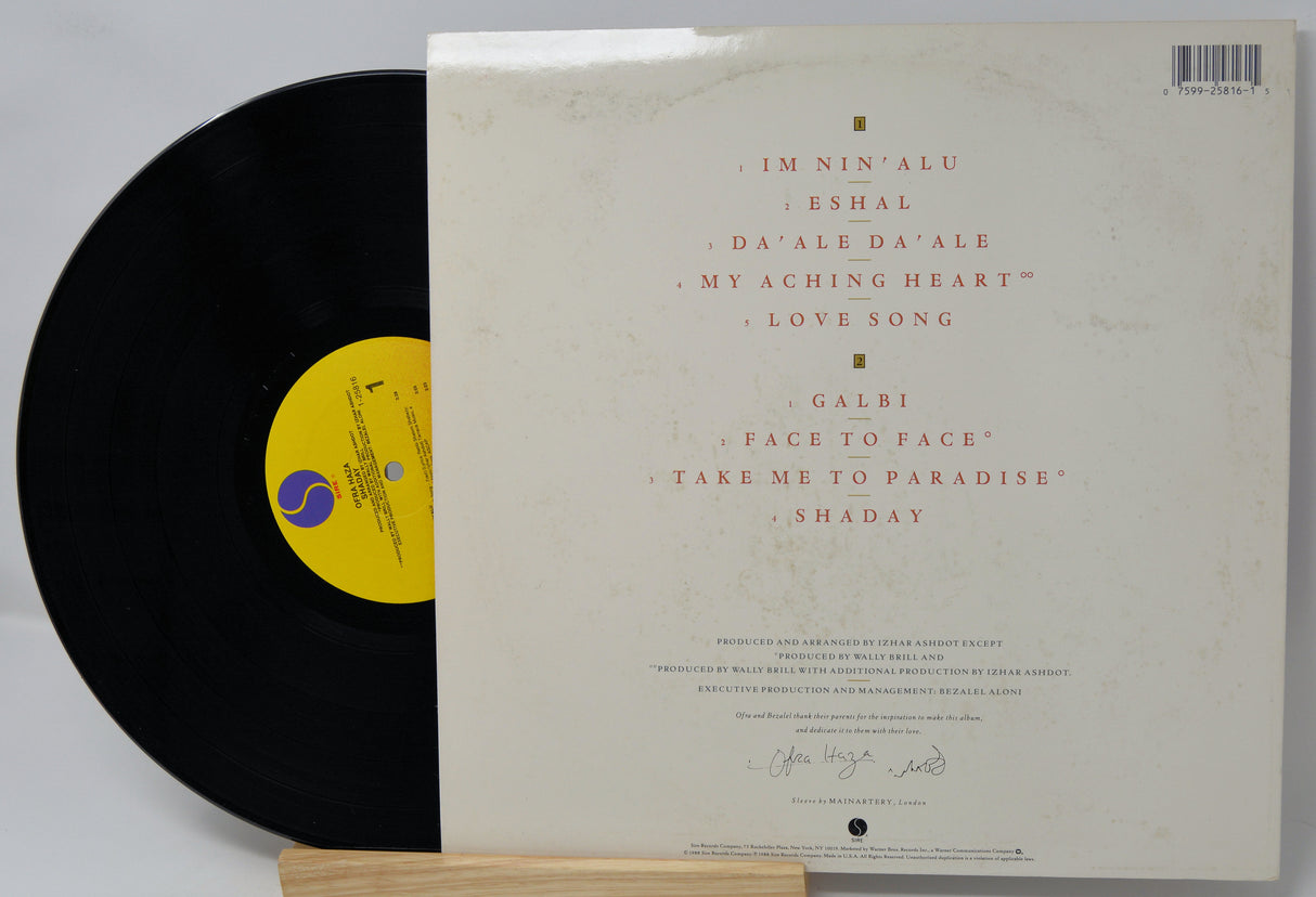 Vinyl record with a white label featuring text and a yellow label on a gray background