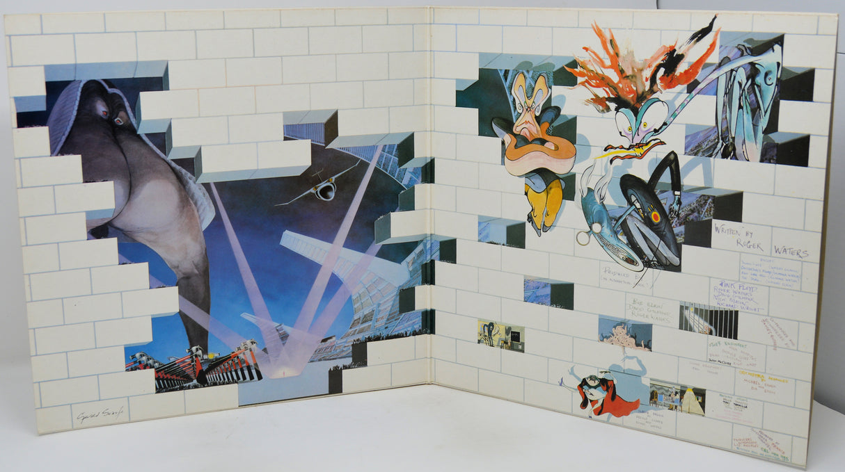 An open art book or album spread, showing two illustrated pages with collage-style fantasy artwork, including a large shark-like figure on the left and multiple anime-inspired characters on the right, photographed against a plain light background.