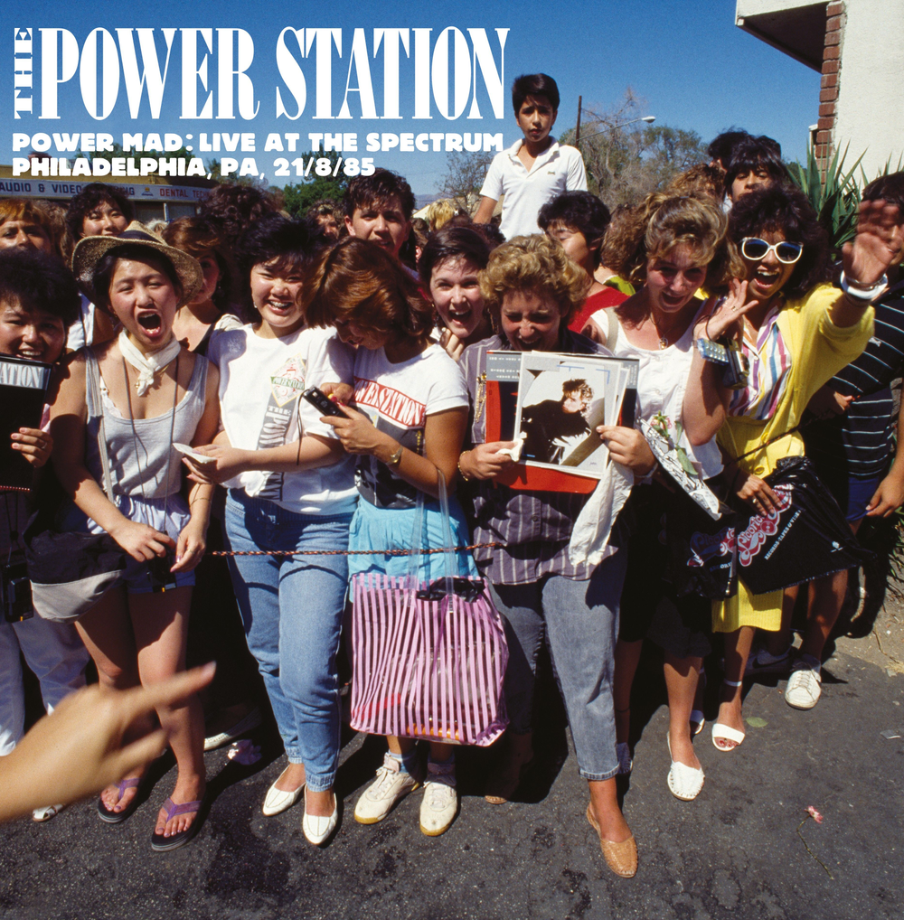 Group of people at a concert with 'The Power Station' album cover