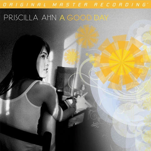 Album cover for Priscilla Ahn's 'A Good Day', featuring a black-and-white photo of the artist at a piano, overlaid with yellow floral graphics and a yellow banner reading 'Original Master Recording'.