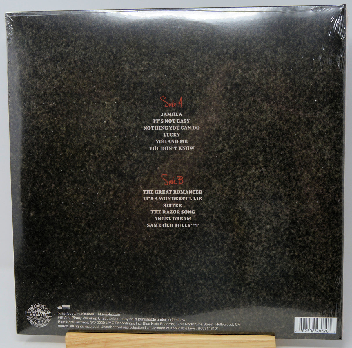 The back cover of a vinyl record album in shrink wrap, showing track listings for Samh A and Samh B in red and white text over a dark textured background.