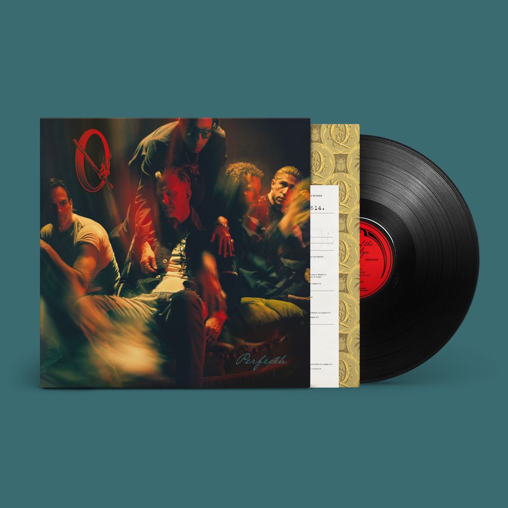 A vinyl record partially pulled from its sleeve, shown on a solid teal background. The album cover features a dark, moody photograph of several men, with a red circular logo near the upper left.