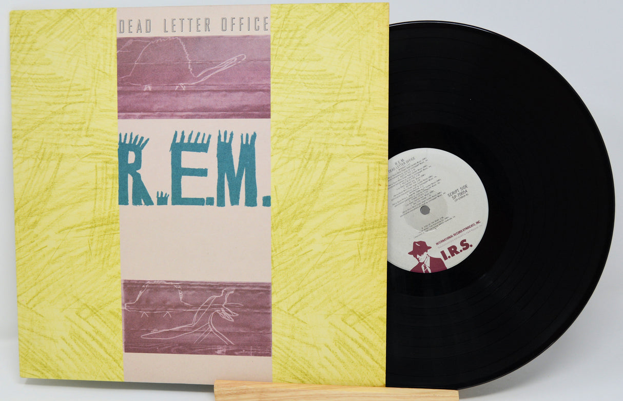 Vinyl record with a yellow cover featuring 'R.E.M.' on a light gray background