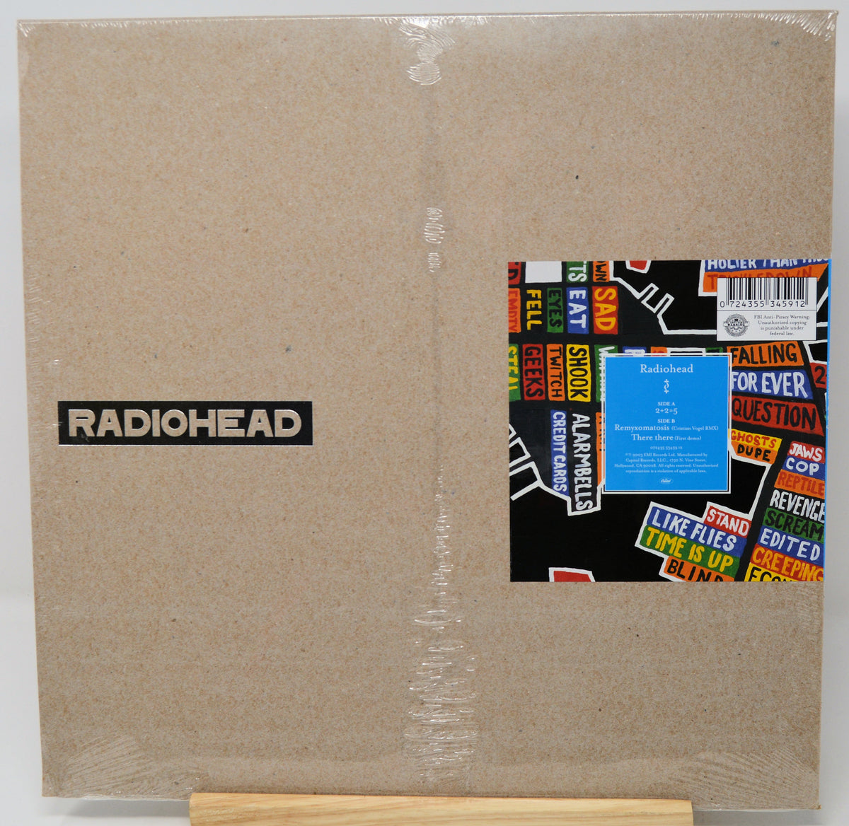 Radiohead 'The End is the Beginning' vinyl record LP cover in its original shrink wrap, displayed on a wooden stand against a white background.