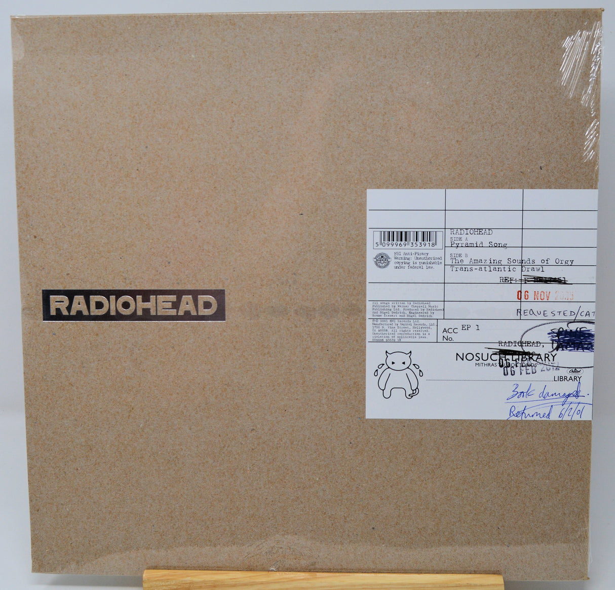 Radiohead 'The Enigma of Cook Tost' vinyl record cover, featuring a textured brown cardboard-style background with a black and white RADIOHEAD logo on the left and a white library label on the right.