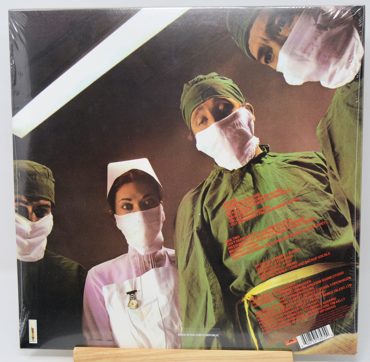 Vinyl record album cover for the band 'The Chameleons' titled 'The Great Illusion', shown in its shrink wrap on a wooden display stand. The cover art depicts three medical professionals in green scrubs and white masks under a bright operating light.
