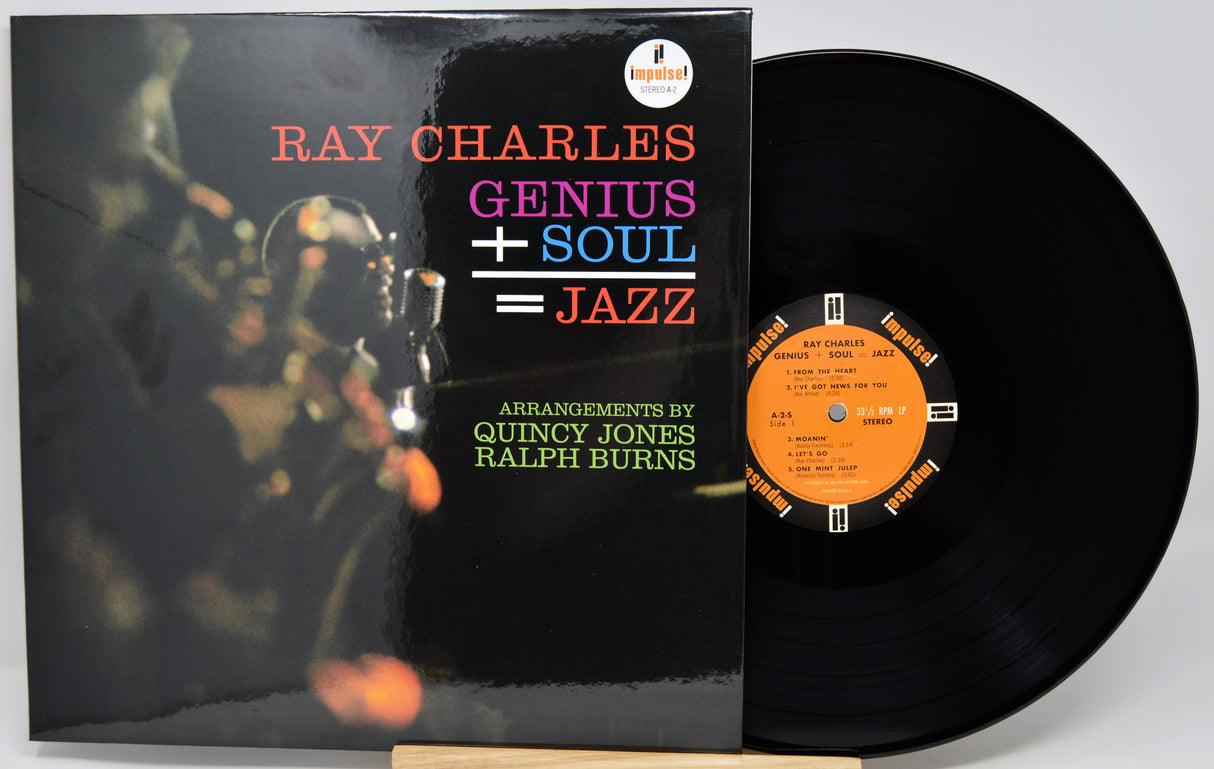 Ray Charles 'Genius + Soul = Jazz' vinyl record album with the black LP disc partially pulled from the sleeve, photographed on a light gray background.