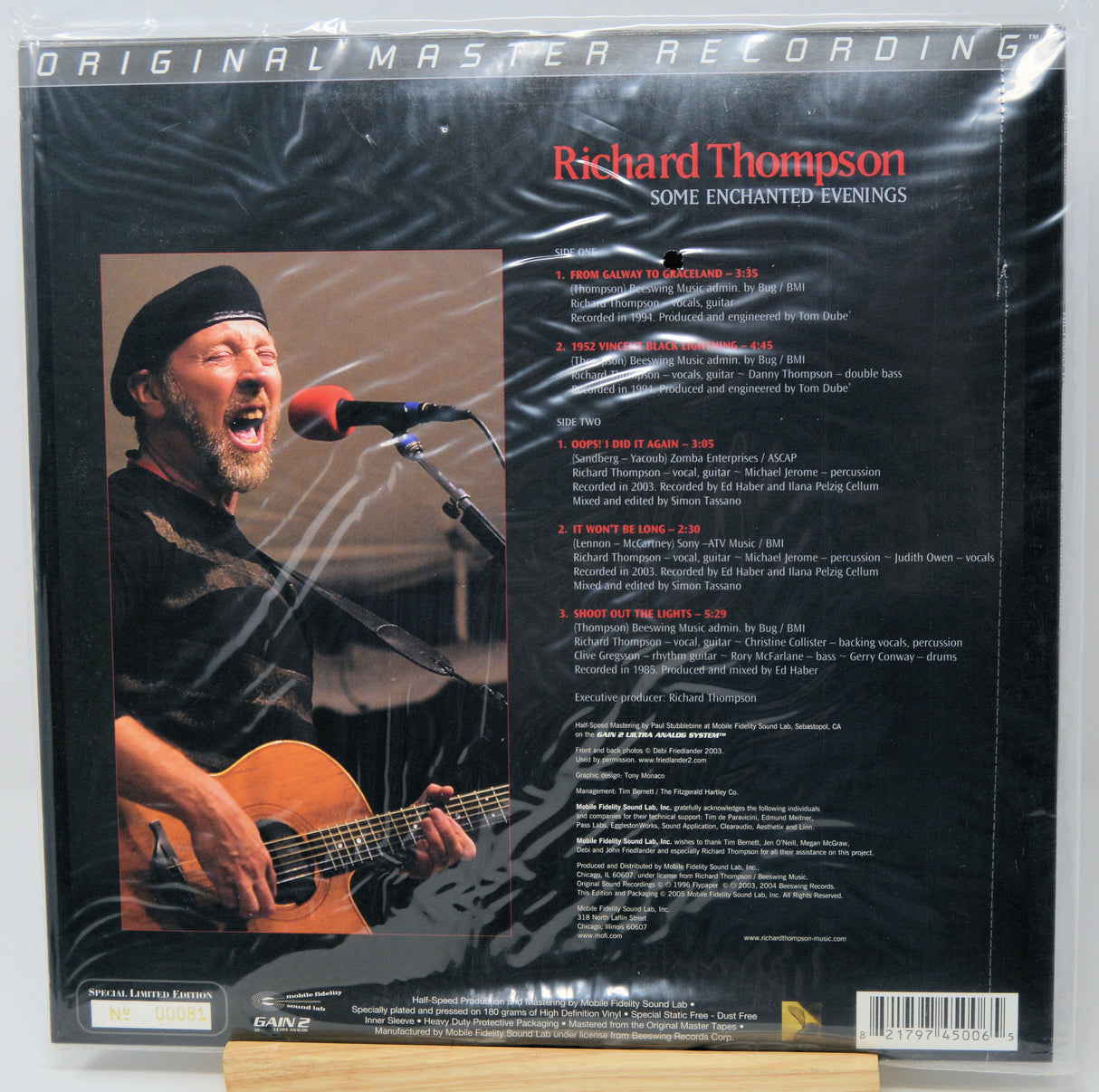 Back cover of Richard Thompson's 'Some Enchanted Evenings' 12-inch vinyl LP, sealed in plastic shrink wrap. The black cover features a photo of the singer performing live with an acoustic guitar and a track list on the right.