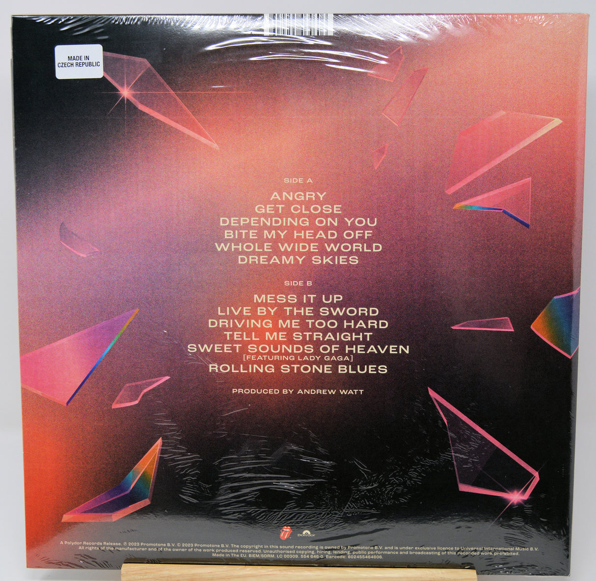 Back cover of a vinyl record sleeve for Rolling Stones 'Angry', sealed in plastic shrink wrap, with tracklist text and abstract pink and black geometric artwork.
