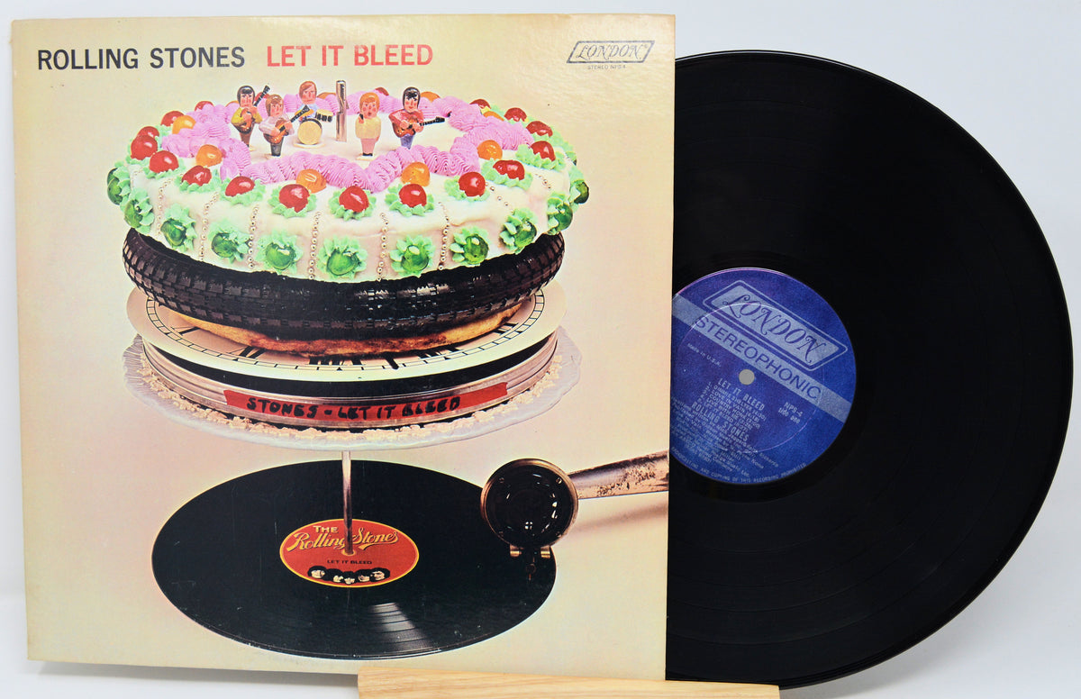 Rolling Stones 'Let It Bleed' vinyl record album with the illustrated cover on the left and the black LP record partially pulled out on the right, photographed against a plain light background.