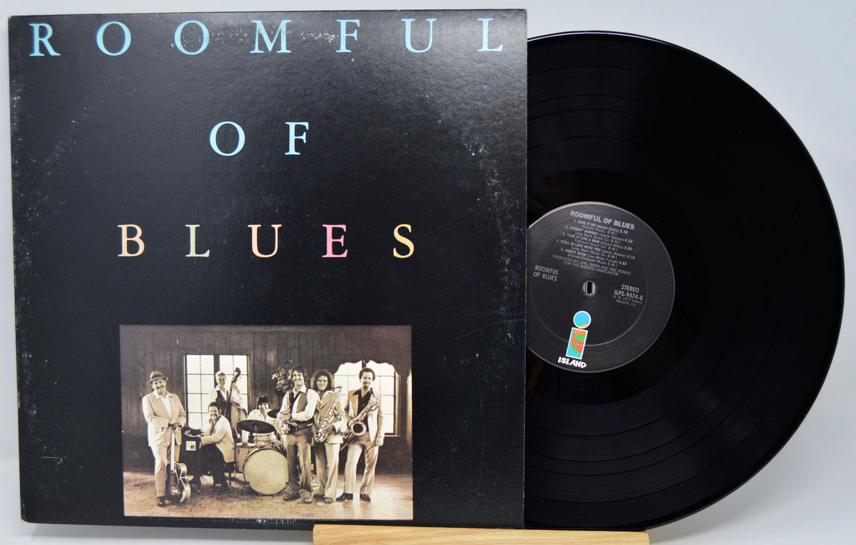A vinyl record album titled 'ROOMFUL OF BLUES' with the black record partially pulled from its sleeve, photographed against a light gray background.