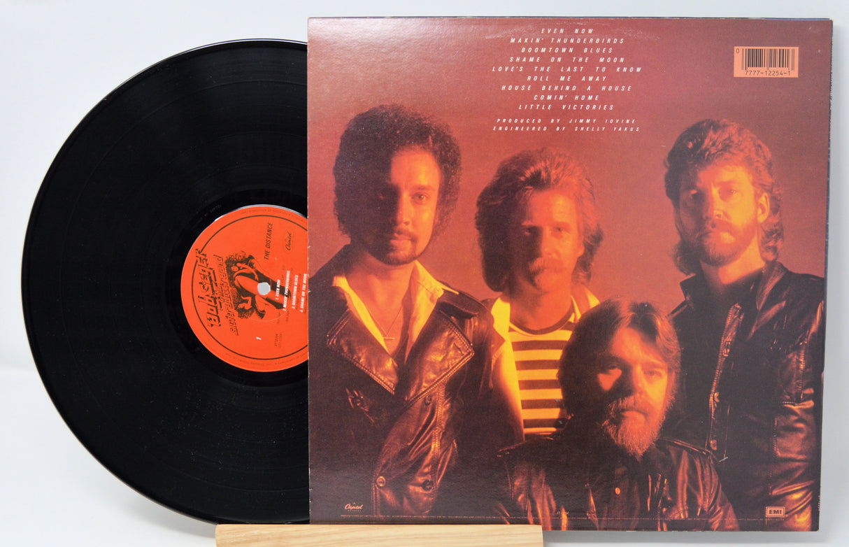 Vinyl record title The Distance by Bob Seger showing the album and the back cover featuring a picture of the band and song listing in text.