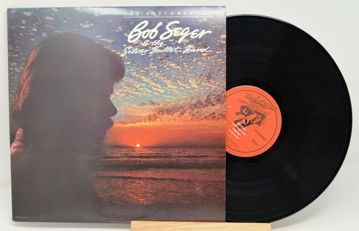 A vinyl record album titled 'Bob Seger - The Distance' with an image of a silhouette of a person against a sunset on the cover.