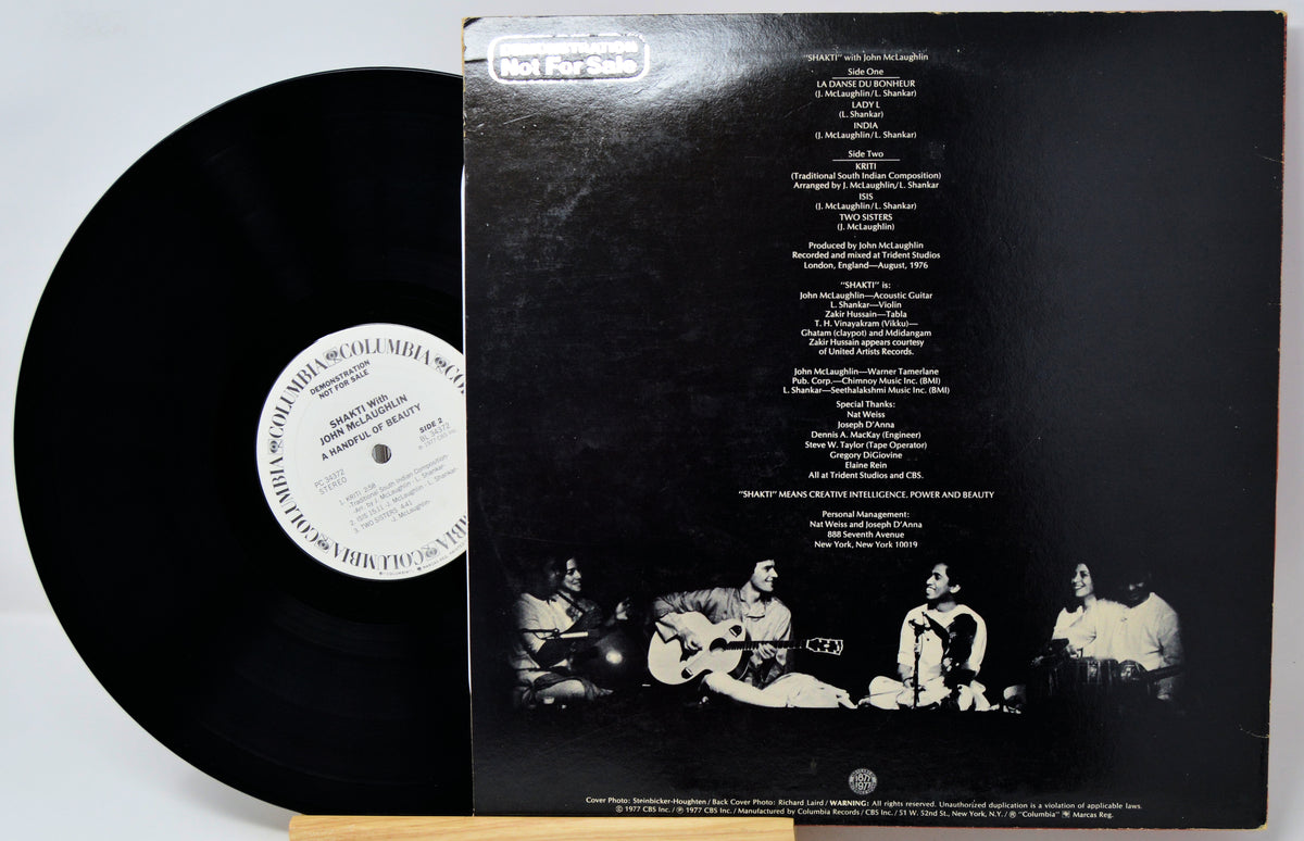 A vinyl record partially pulled from its black outer sleeve, showing the back cover with printed tracklist and a black-and-white band photo. The record label reads Columbia Records.