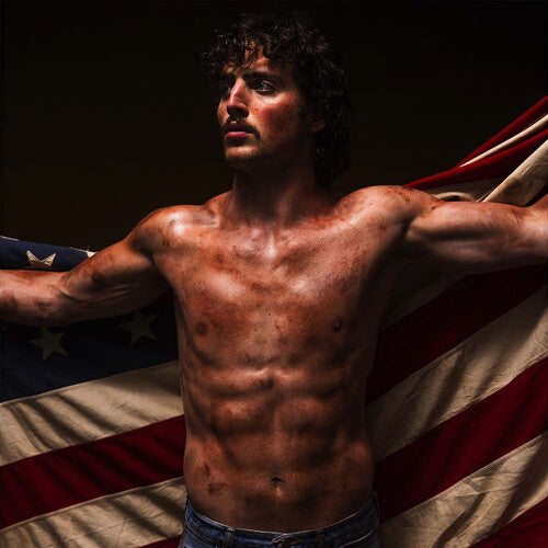 Shirtless man standing in front of an American flag, portraying a bold and patriotic vibe