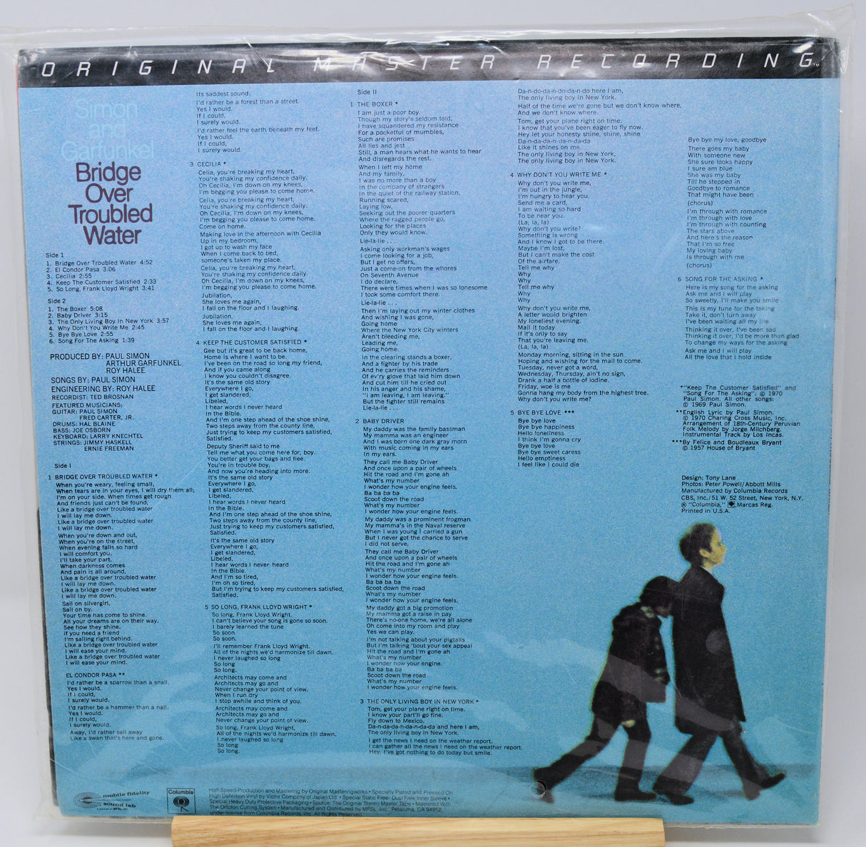 Back cover of a vinyl album with text and a minimalist illustration of two people walking on a snowy landscape.