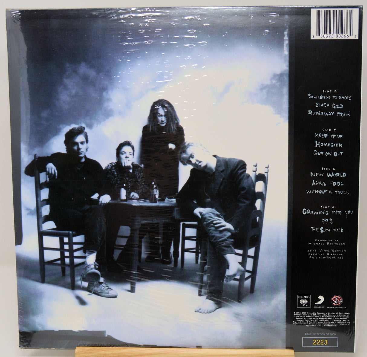 Album cover with a black and white photo of four people around a table, with text on the right side.
