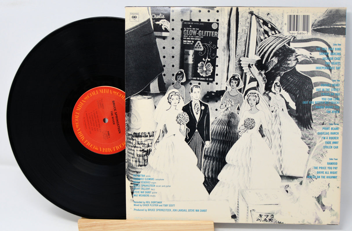 Vinyl record and back cover of Bruce Spingsteen album titled 'The River' showing paper cutouts of people in a wedding party.