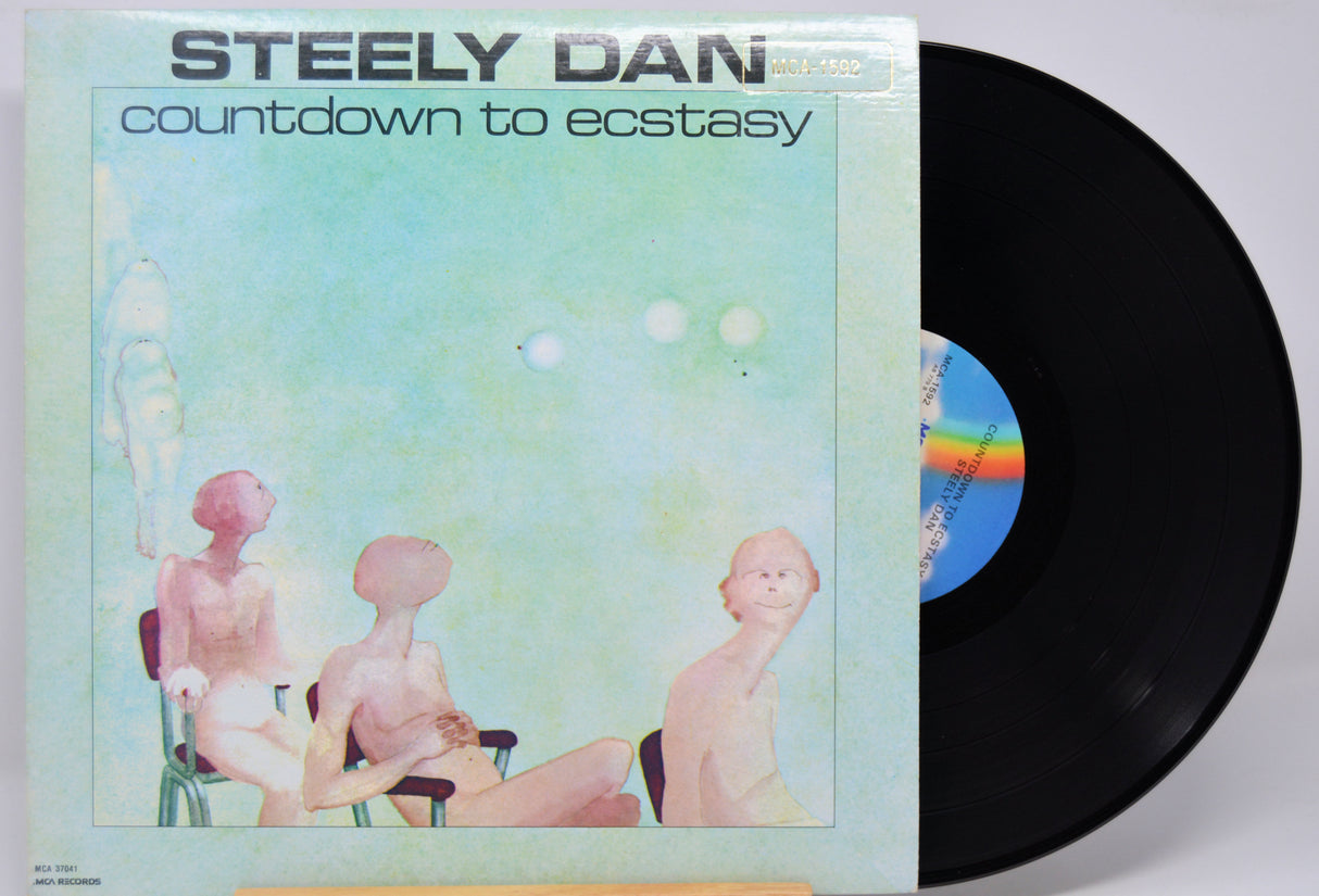 Vinyl record with 'Steely Dan Countdown to Ecstacy' album cover showing three people and a rainbow.