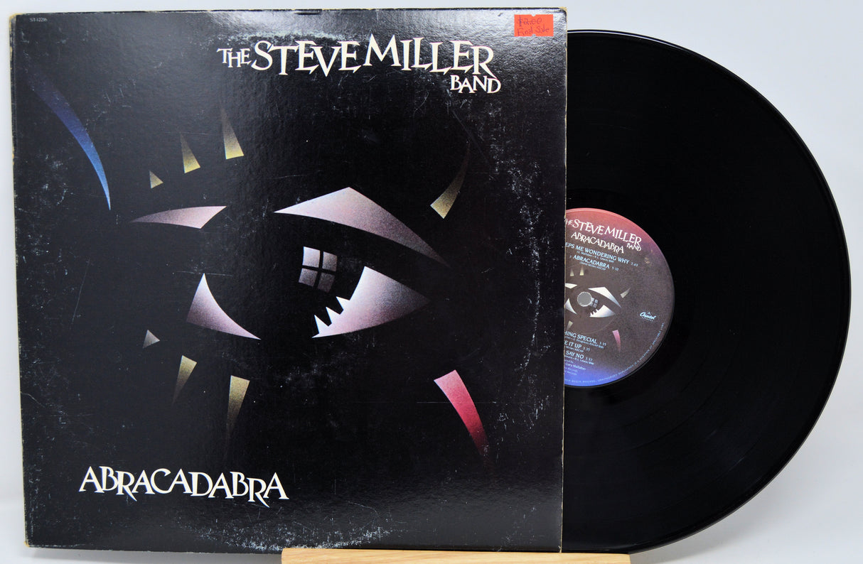 Vinyl record and cover of 'Abracadabra' by The Steve Miller Band on a white background