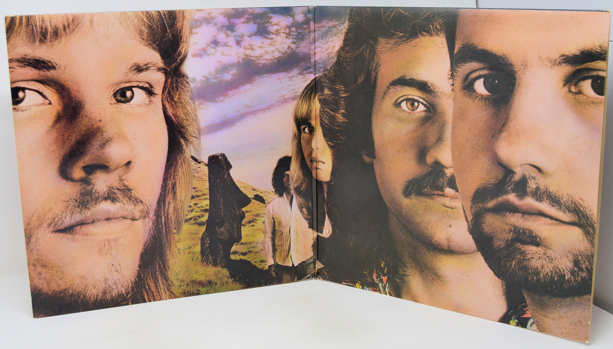 A vintage album cover or printed panel featuring close-up portraits of three men with a small scenic landscape in the center, photographed against a plain light background.