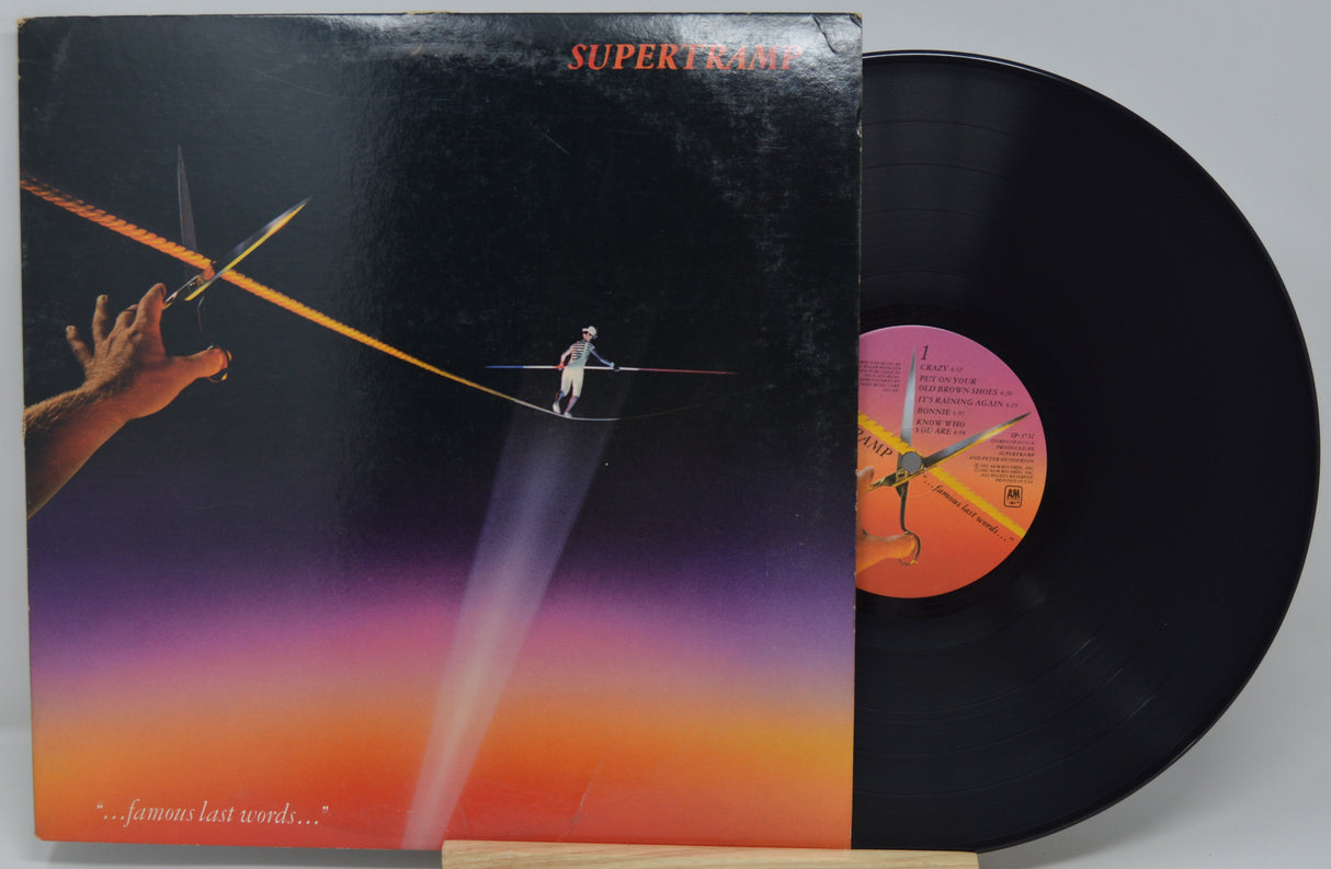 Vinyl record with a colorful cover featuring a person on a tightrope against a sunset sky.