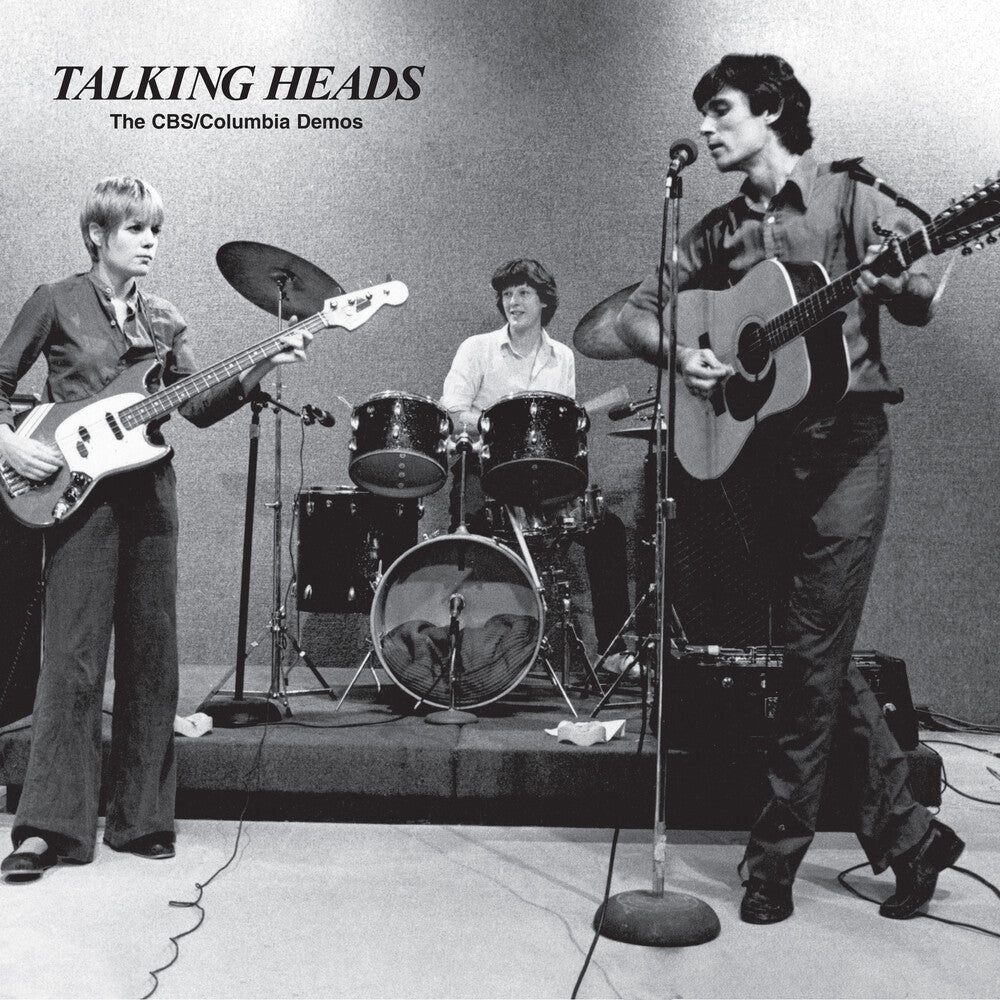 Black and white photo of a band performing on stage with 'Talking Heads' text above.