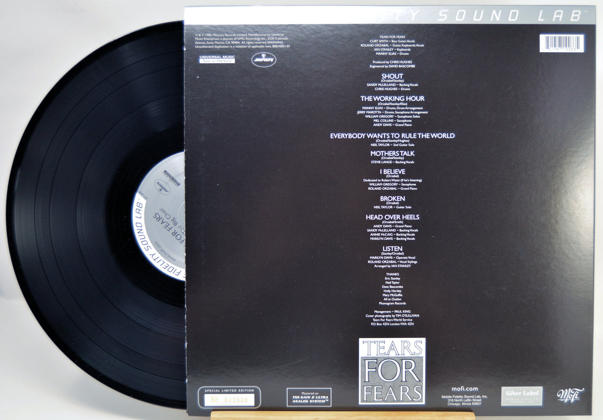 A vinyl record partially pulled from its sleeve, showing the back of the packaging. The black record is visible on the left, and the sleeve is black with white printed tracklist text and the title 'TEARS FOR FEARS' near the bottom.