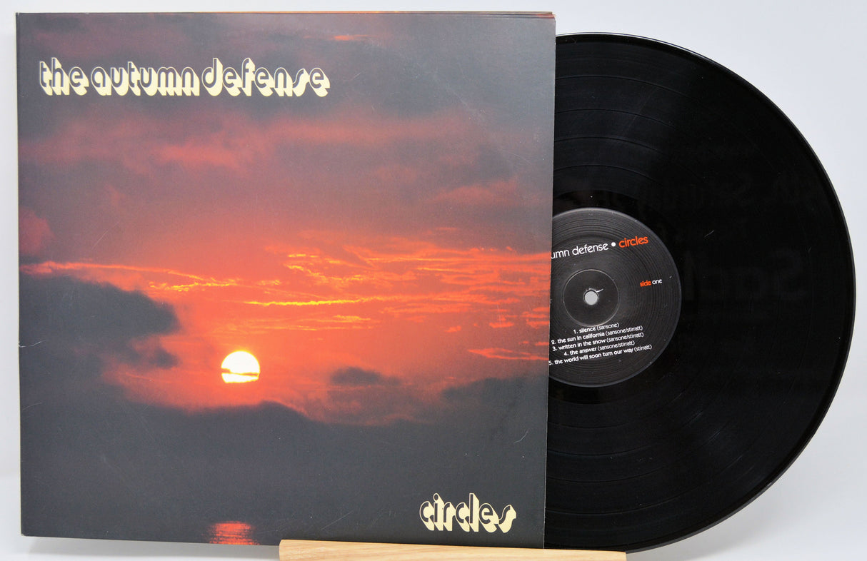 Front cover of The Autumn Defense Circles vinyl record with dramatic sunset and band logo