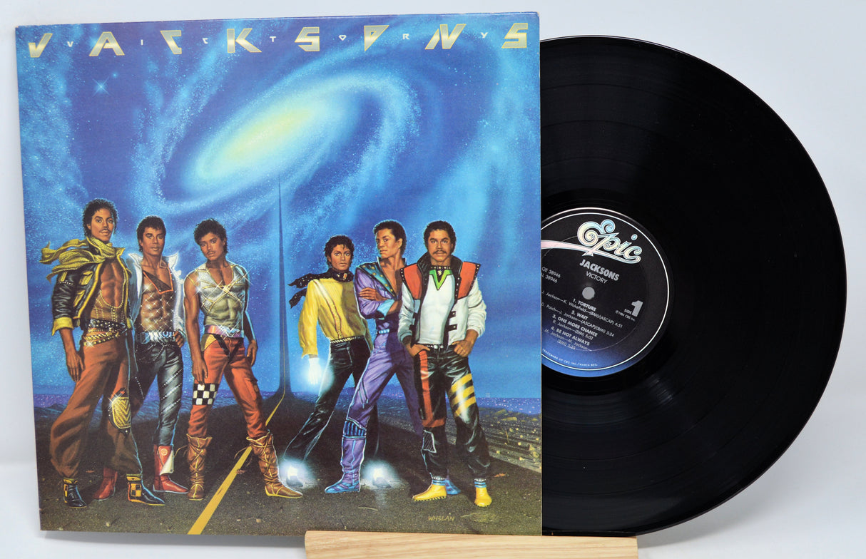 A vinyl record titled 'Jacksons - Victory' with the band The Jacksons on the album cover, displayed next to a turntable.