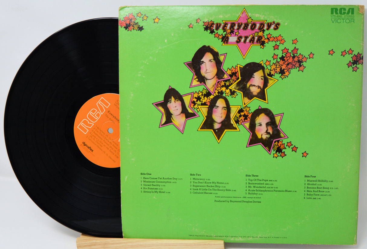 Vinyl record with a green cover featuring star designs and faces, on a white background.